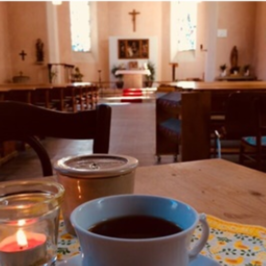 Durch die geöffnete Tür der Kirche von Heckenbach sieht man in den erleuchteten Kirchenraum.